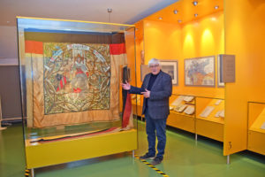 Prof. Dr. Friedhelm Brusniak in den Ausstellungsräumen des Sängermuseums. Die Fahne stammt aus dem Jahr 1861 und hat einen besonderen ideellen Wert. Foto: am